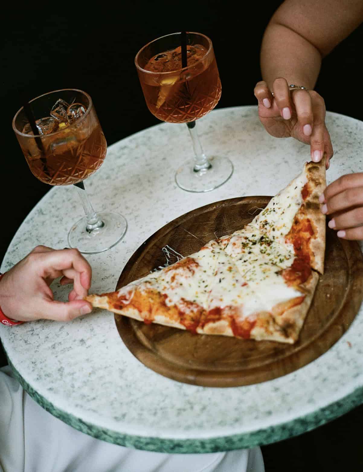 Couple sharing a slice of pizza and cocktails during an Italy wedding welcome dinner